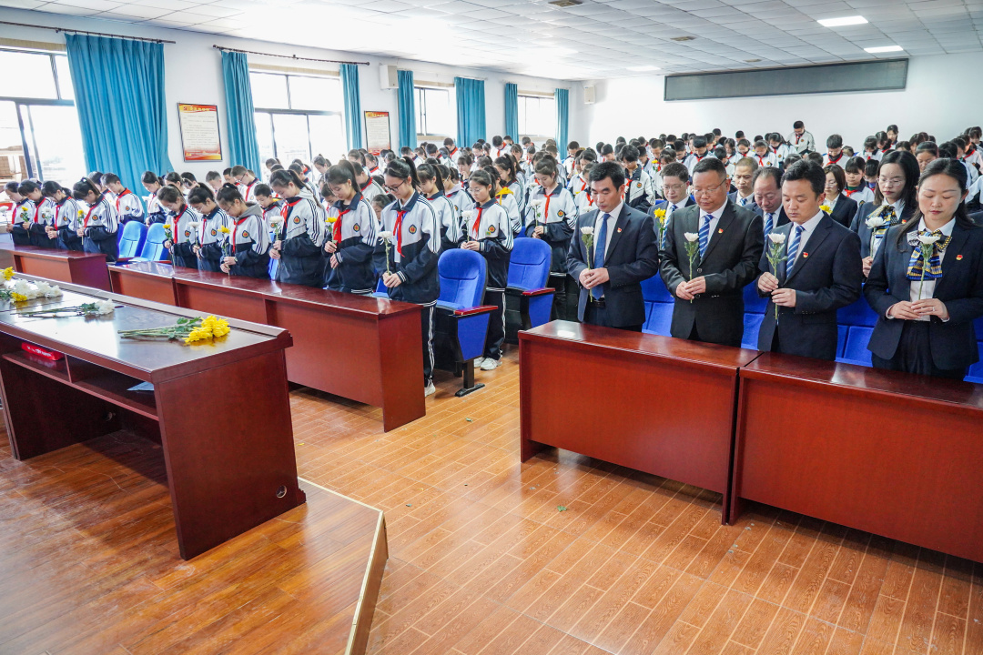 師生們開展網(wǎng)上祭奠活動，手拿鮮花面對大屏幕低頭默哀。.jpg